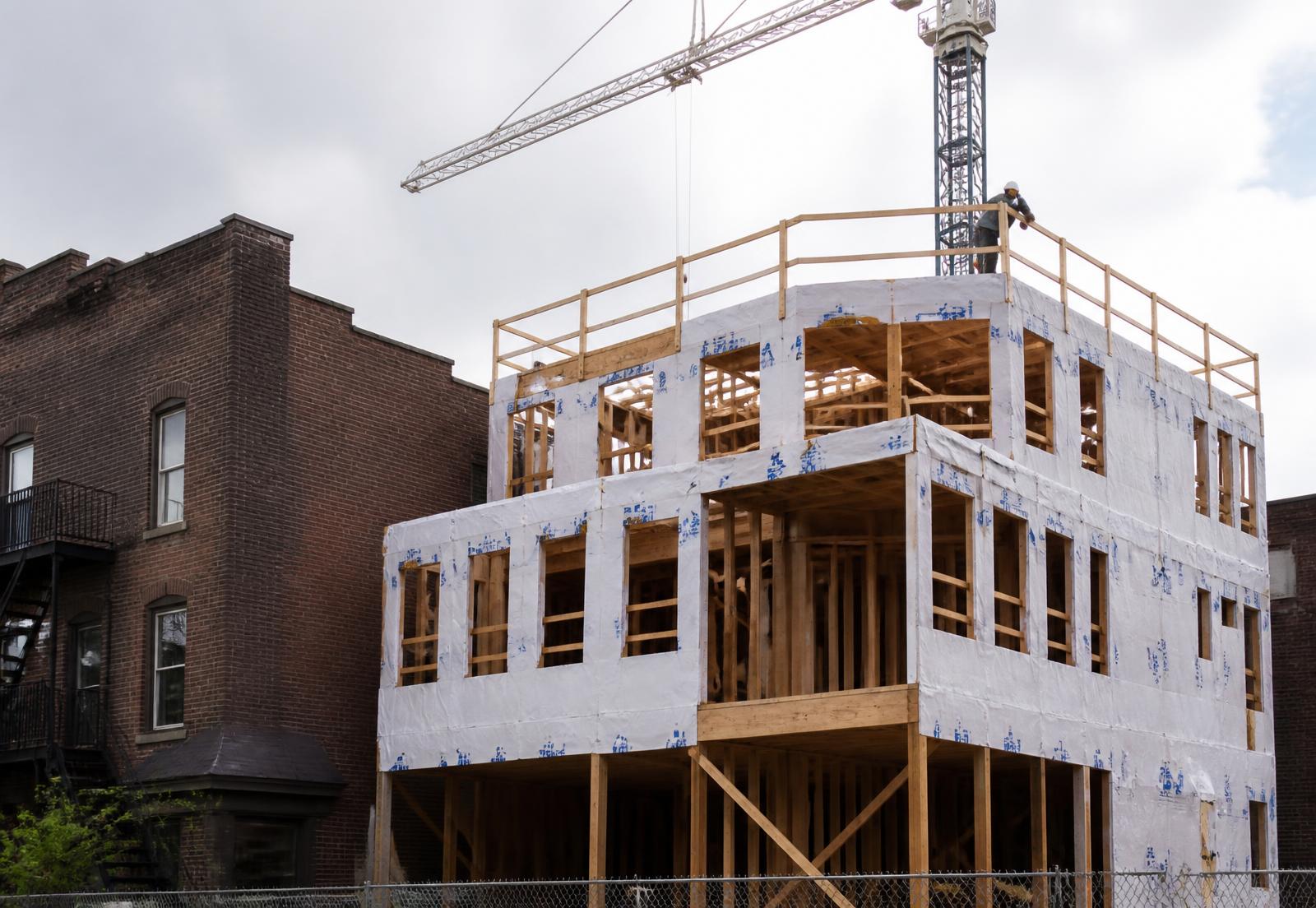 New residential construction framing next to historic brick buildings in NoDa